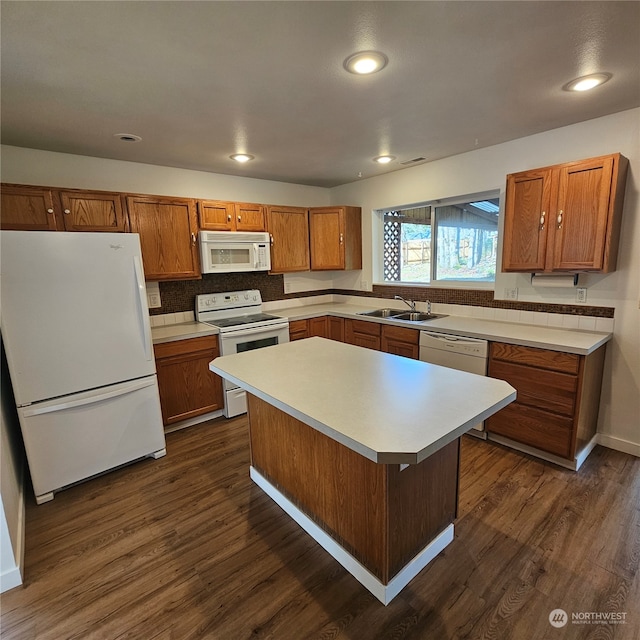 kitchen featuring sink, dark wood-type flooring, white appliances, a breakfast bar, and a kitchen island