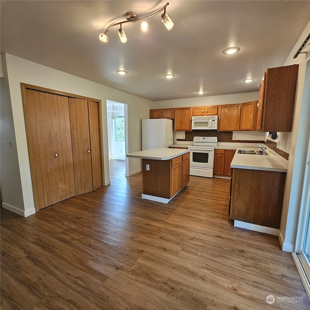 kitchen featuring white appliances, sink, hardwood / wood-style flooring, tasteful backsplash, and a kitchen island