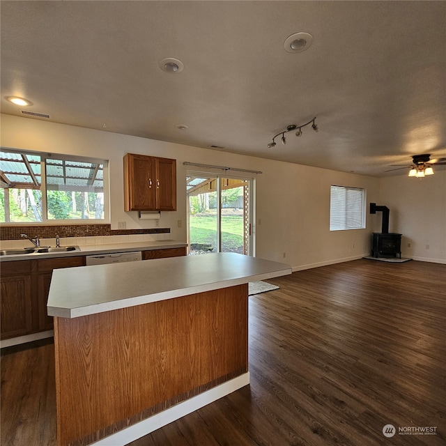 kitchen featuring a center island, a wood stove, dark wood-type flooring, and sink