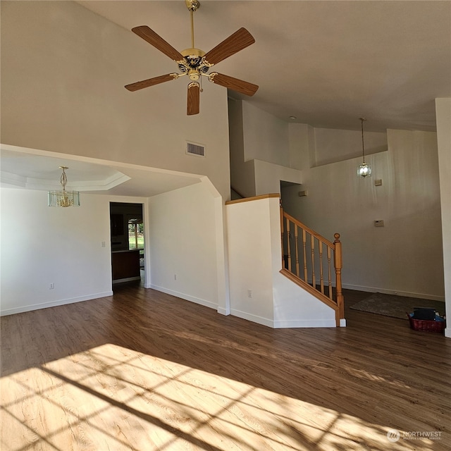 unfurnished living room featuring ceiling fan with notable chandelier, wood-type flooring, and high vaulted ceiling