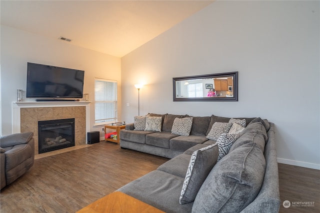 living room featuring a tile fireplace, wood-type flooring, plenty of natural light, and lofted ceiling