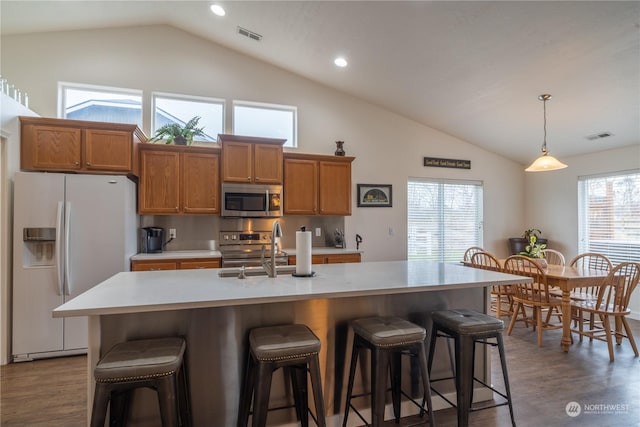 805 S Hamilton Rd, Moses Lake, WA 98837 - kitchen with stainless steel appliances, brown cabinetry, a sink, high vaulted ceiling, and light countertops