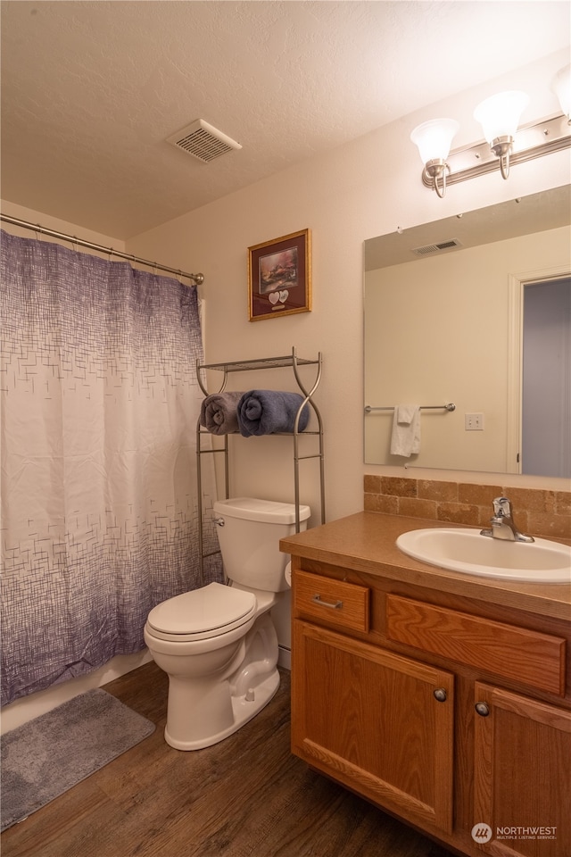 bathroom with a textured ceiling, vanity, hardwood / wood-style flooring, and toilet