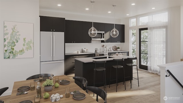 kitchen with a center island with sink, plenty of natural light, white refrigerator, and a breakfast bar