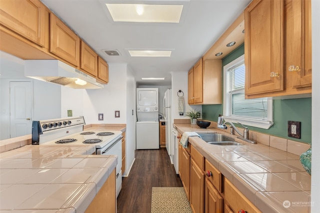 kitchen featuring sink, dark hardwood / wood-style flooring, tile countertops, electric stove, and stacked washer and clothes dryer