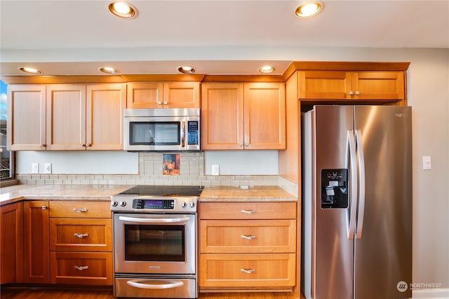 kitchen featuring backsplash, light stone countertops, dark wood-type flooring, and appliances with stainless steel finishes