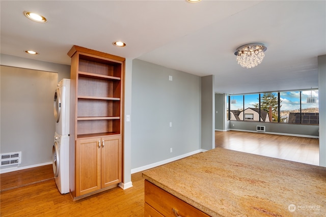 interior space with light hardwood / wood-style floors, stacked washer and clothes dryer, and an inviting chandelier