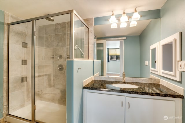 bathroom featuring a shower with door and vanity