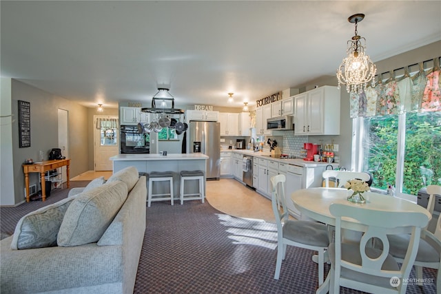 dining area featuring light carpet, sink, and a chandelier