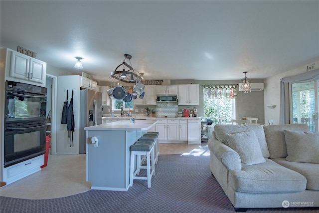 kitchen featuring stainless steel appliances, a kitchen island, hanging light fixtures, and white cabinets