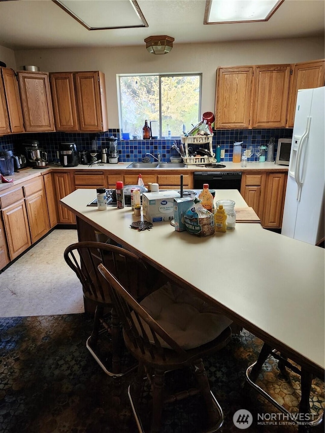 kitchen featuring dishwasher, decorative backsplash, white refrigerator with ice dispenser, and light countertops