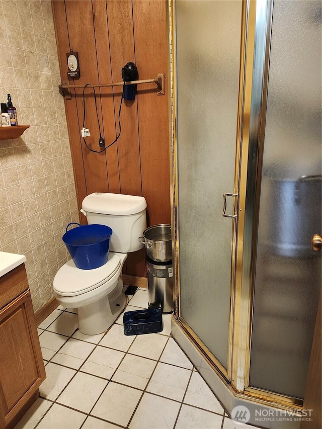 full bath featuring tile patterned floors, toilet, a stall shower, and tile walls