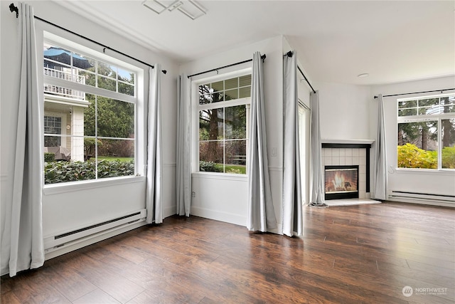 unfurnished living room with a fireplace, dark hardwood / wood-style flooring, baseboard heating, and a wealth of natural light