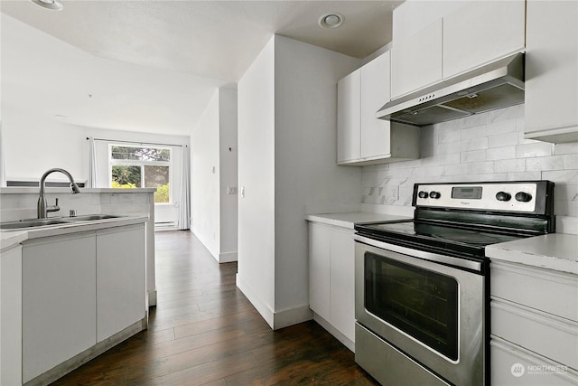 kitchen with dark wood-type flooring, sink, wall chimney exhaust hood, stainless steel electric range oven, and white cabinetry