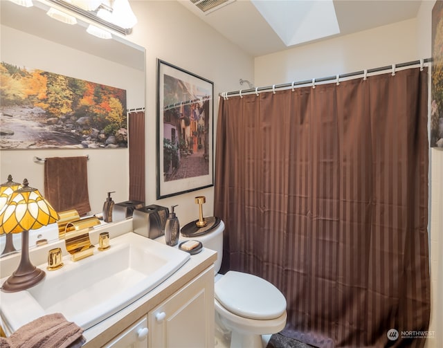 bathroom featuring a shower with shower curtain, vanity, toilet, and a skylight