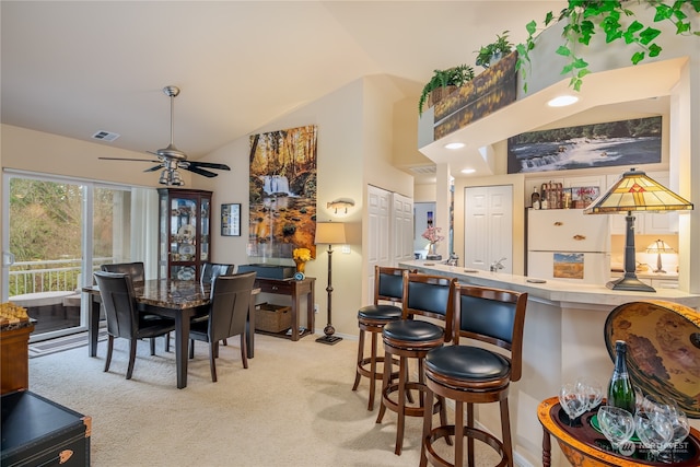 carpeted dining room with ceiling fan and lofted ceiling