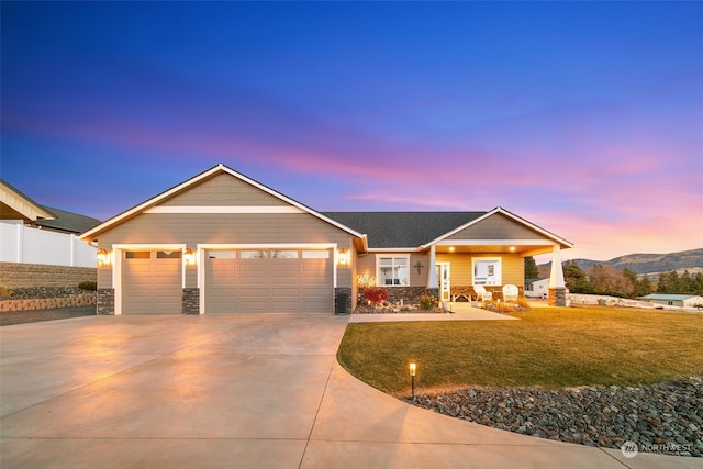 view of front of home with a garage, concrete driveway, stone siding, and a front lawn