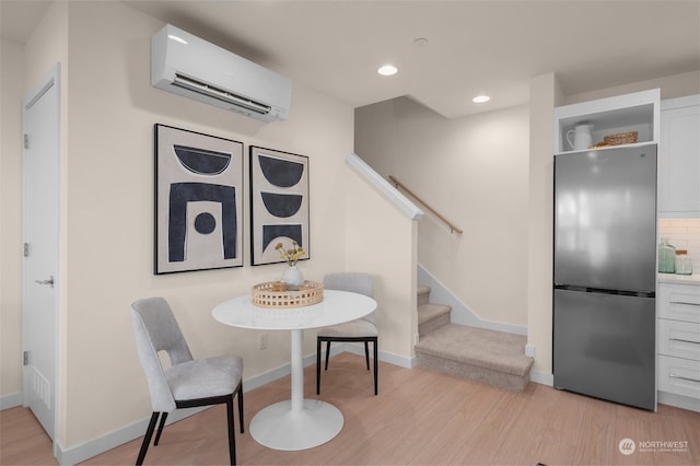 dining area with light wood-type flooring and an AC wall unit