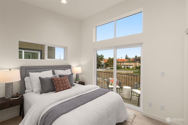 carpeted bedroom featuring access to exterior and a towering ceiling