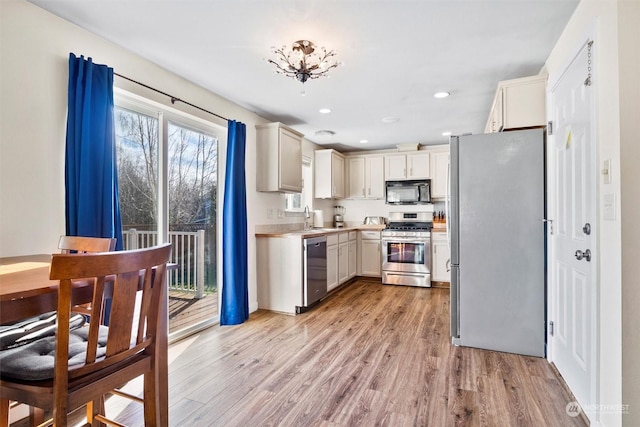 kitchen featuring appliances with stainless steel finishes, sink, and light hardwood / wood-style flooring