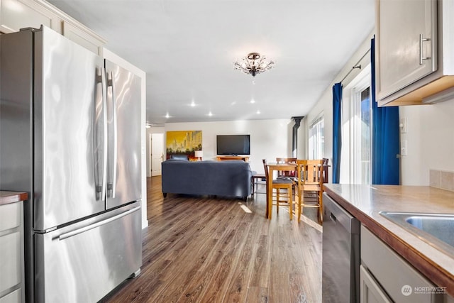 kitchen featuring appliances with stainless steel finishes, dark wood-type flooring, gray cabinetry, and sink