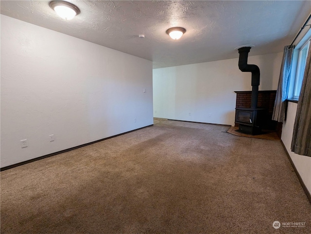 unfurnished living room featuring carpet floors, a textured ceiling, and a wood stove