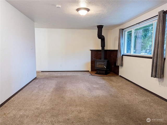 unfurnished living room with a textured ceiling, a wood stove, and carpet floors