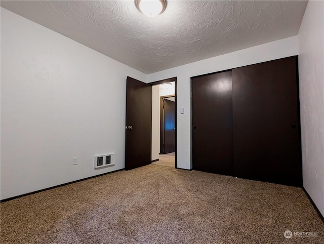 unfurnished bedroom featuring a closet, light carpet, and a textured ceiling