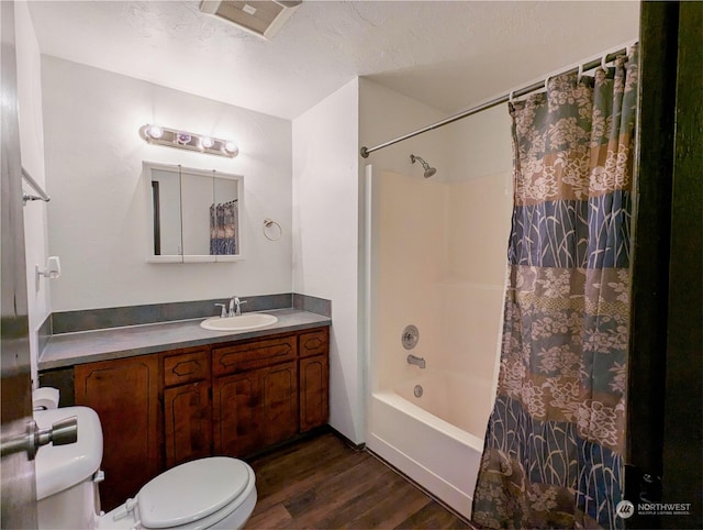 full bathroom featuring shower / tub combo with curtain, hardwood / wood-style flooring, vanity, a textured ceiling, and toilet