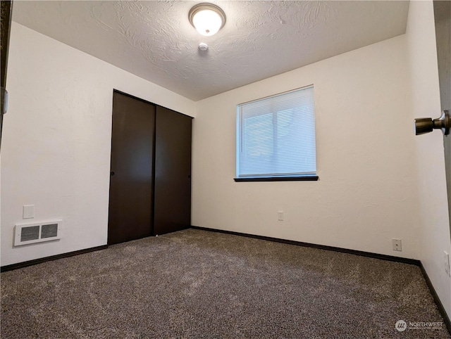 unfurnished bedroom featuring carpet, a textured ceiling, and a closet