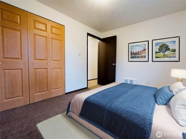 carpeted bedroom with a textured ceiling and a closet