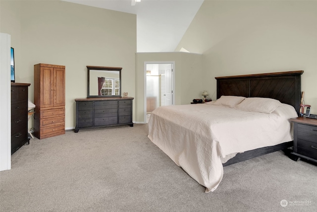 bedroom with ensuite bathroom, light carpet, and high vaulted ceiling