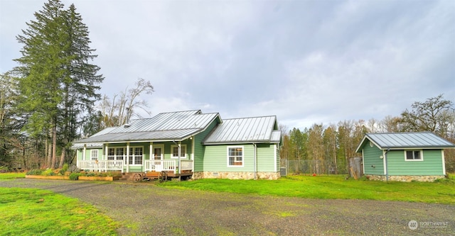 view of front of property featuring covered porch, an outdoor structure, and a front yard