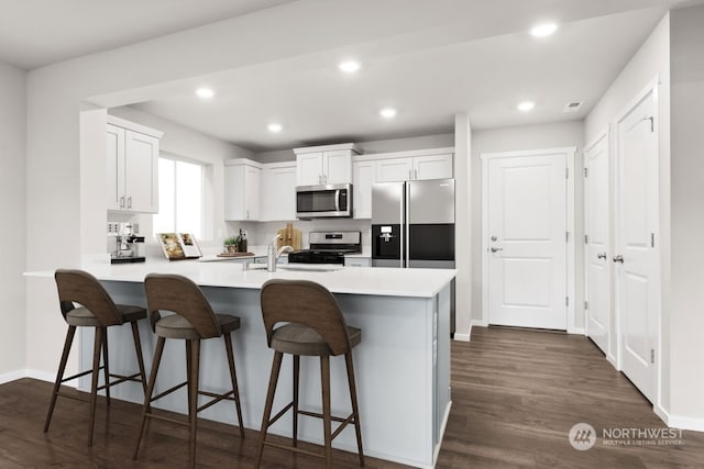 kitchen featuring kitchen peninsula, a kitchen breakfast bar, stainless steel appliances, and white cabinetry