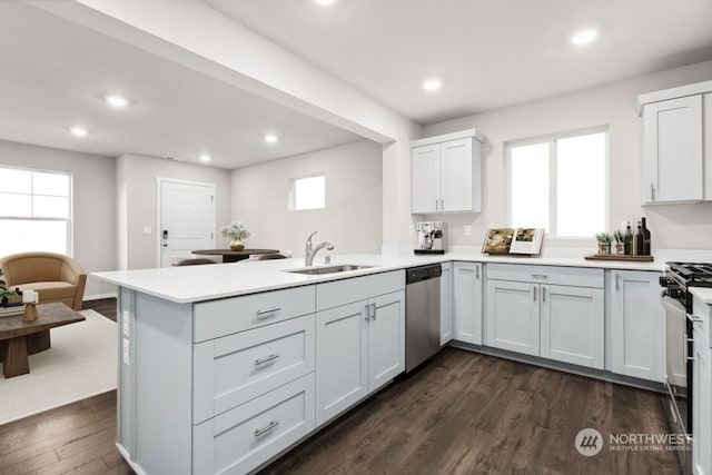 kitchen featuring kitchen peninsula, sink, white cabinets, and stainless steel appliances