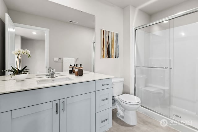 bathroom featuring vanity, a shower with shower door, and toilet