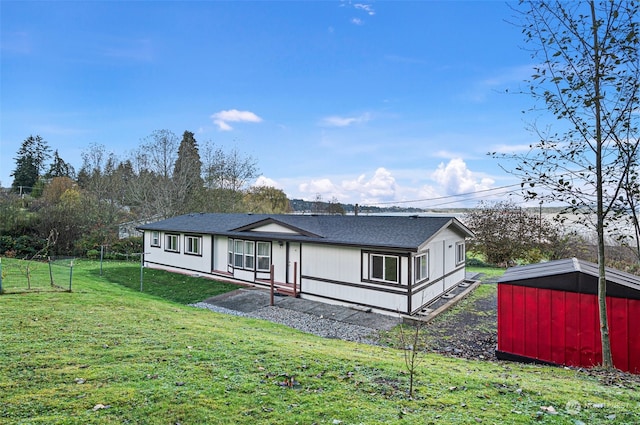 rear view of house with a storage unit and a lawn