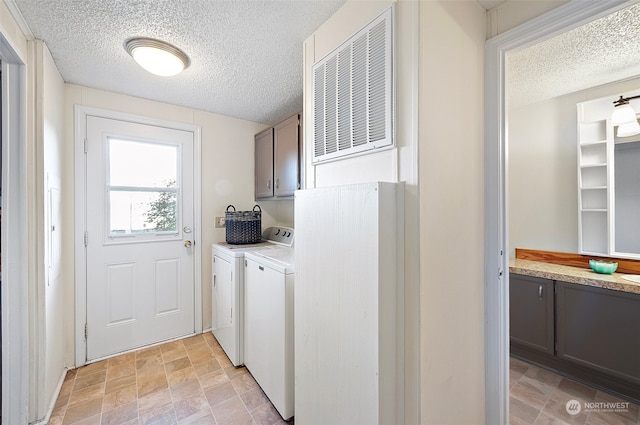 laundry area with cabinets, a textured ceiling, and washing machine and clothes dryer