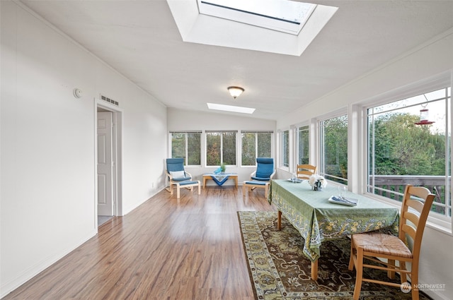 sunroom featuring lofted ceiling with skylight