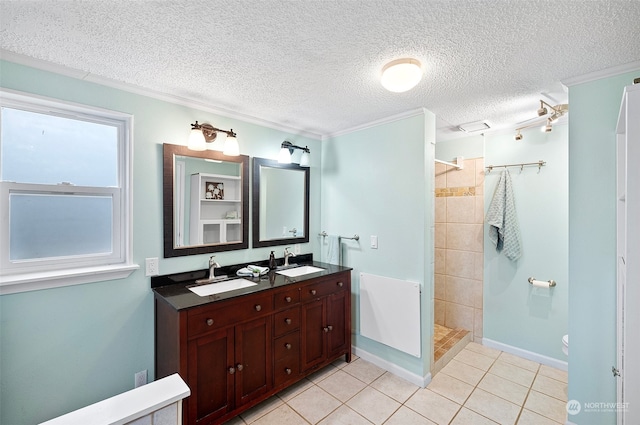 bathroom with vanity, tile patterned floors, ornamental molding, tiled shower, and a textured ceiling