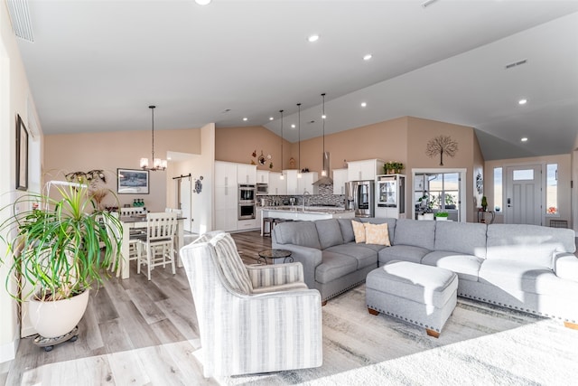 living room featuring sink, an inviting chandelier, high vaulted ceiling, and light wood-type flooring