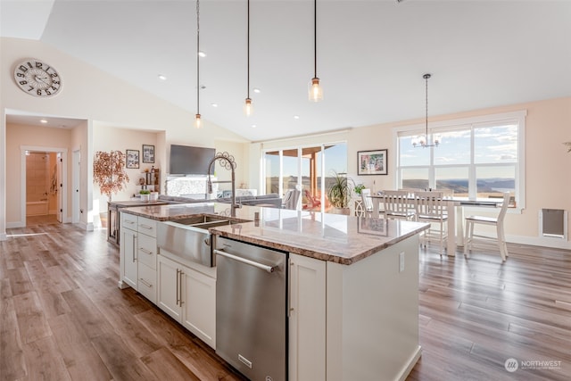 kitchen featuring light stone countertops, light wood-type flooring, a kitchen island with sink, decorative light fixtures, and white cabinets