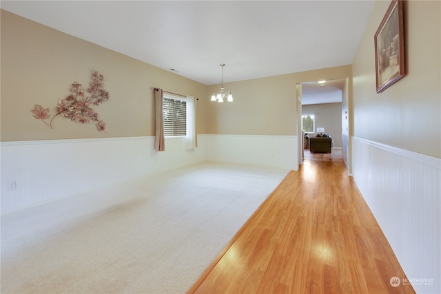 spare room featuring hardwood / wood-style flooring and a chandelier