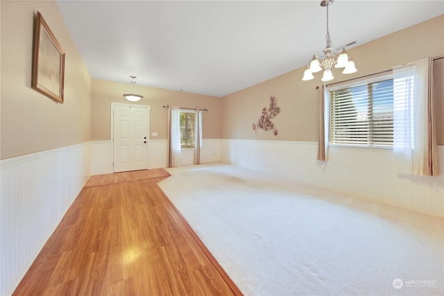 unfurnished room with plenty of natural light, light hardwood / wood-style floors, and a notable chandelier