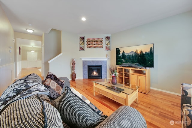 living room featuring a tiled fireplace and hardwood / wood-style floors