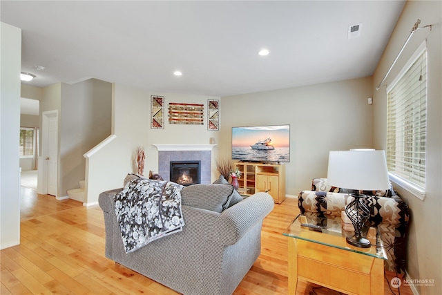 living room featuring a tiled fireplace and light hardwood / wood-style flooring