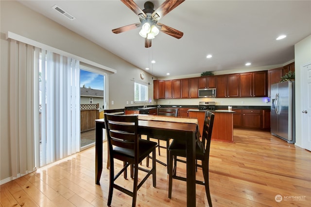 dining space with ceiling fan, sink, and light wood-type flooring