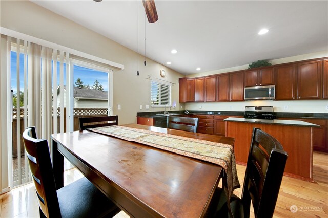 kitchen featuring sink, a center island, hanging light fixtures, appliances with stainless steel finishes, and light wood-type flooring