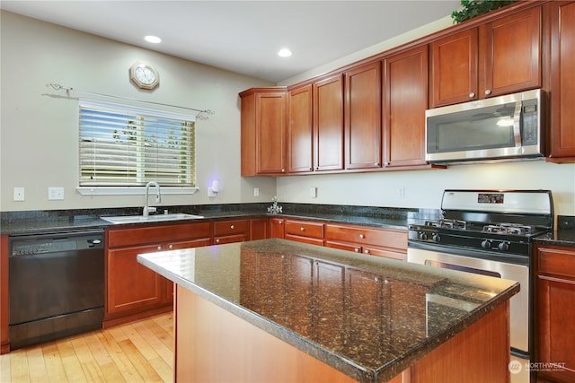 kitchen featuring dark stone counters, a center island, light wood-type flooring, and appliances with stainless steel finishes