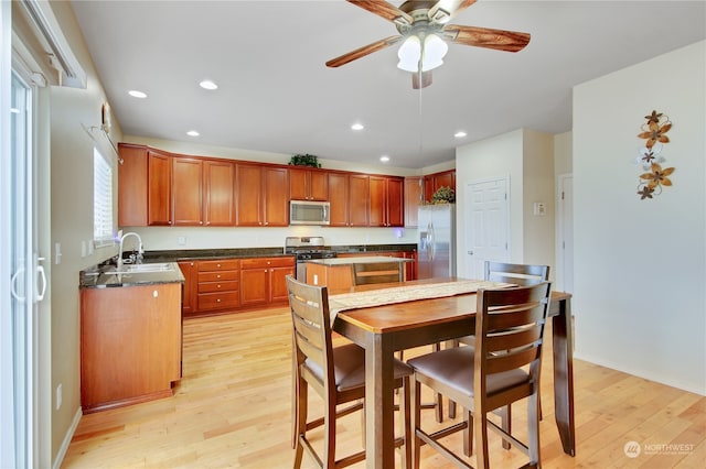 kitchen featuring ceiling fan, sink, stainless steel appliances, and light hardwood / wood-style floors